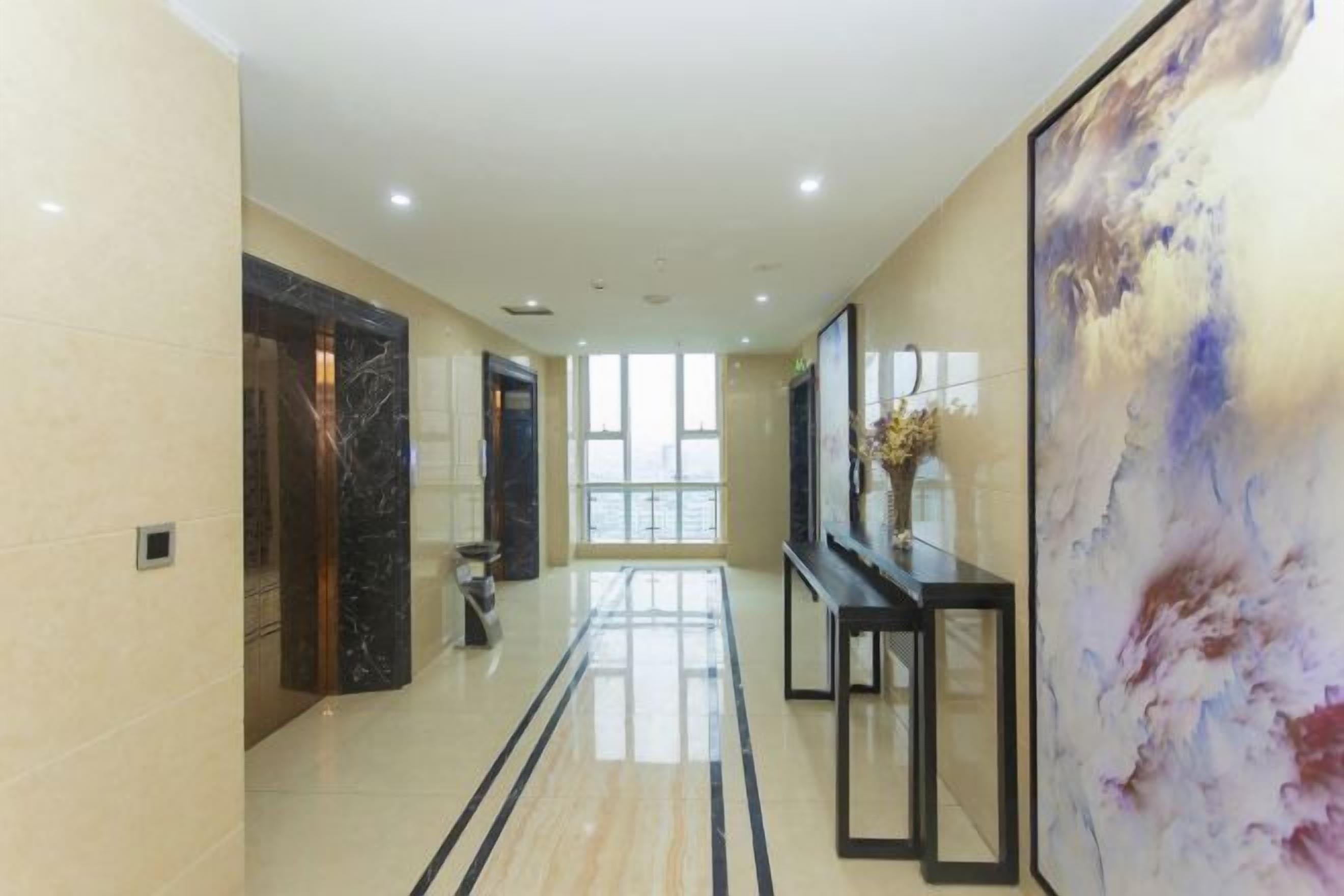 A hallway with a marble floor, a black reception desk, and a large abstract painting.