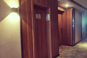 A hallway with wooden doors and a carpeted floor. - Platinum Celebrity Hotel (Chongzhou)