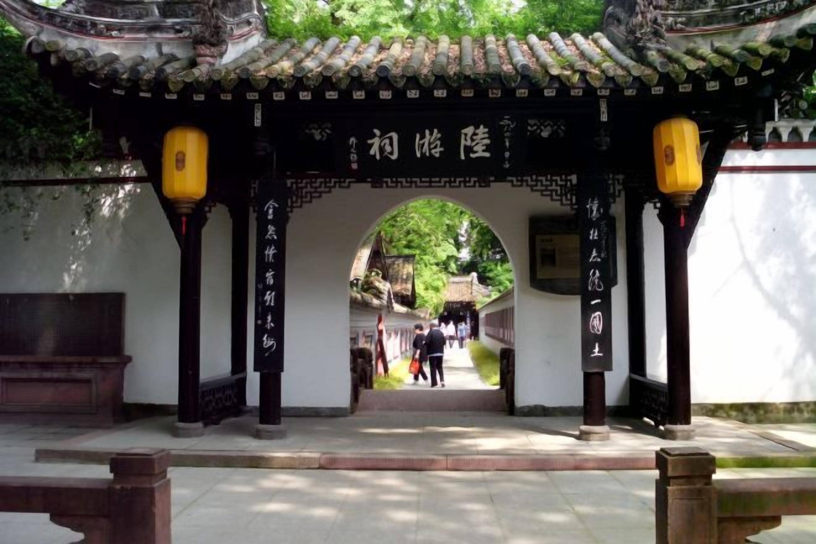 An entrance with a traditional archway, lanterns, and a pathway leading into a building.