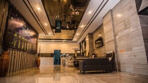 A modern lobby with a marble floor, a reception desk, a seating area, and a large artwork on the wall. - Platinum Celebrity Hotel (Chongzhou)