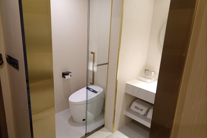 A modern bathroom with a glass-enclosed shower, a white toilet, and a white sink with a mirror above it.