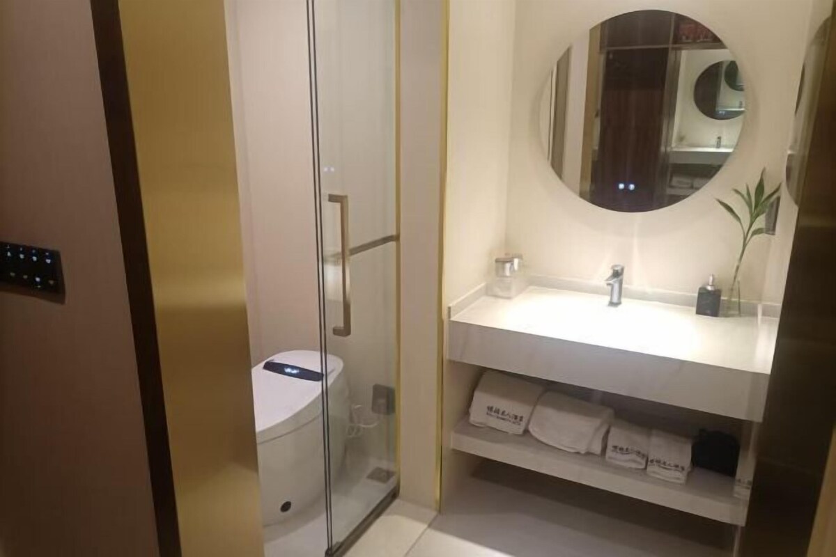A bathroom with a toilet, a sink, a mirror, and a towel rack.