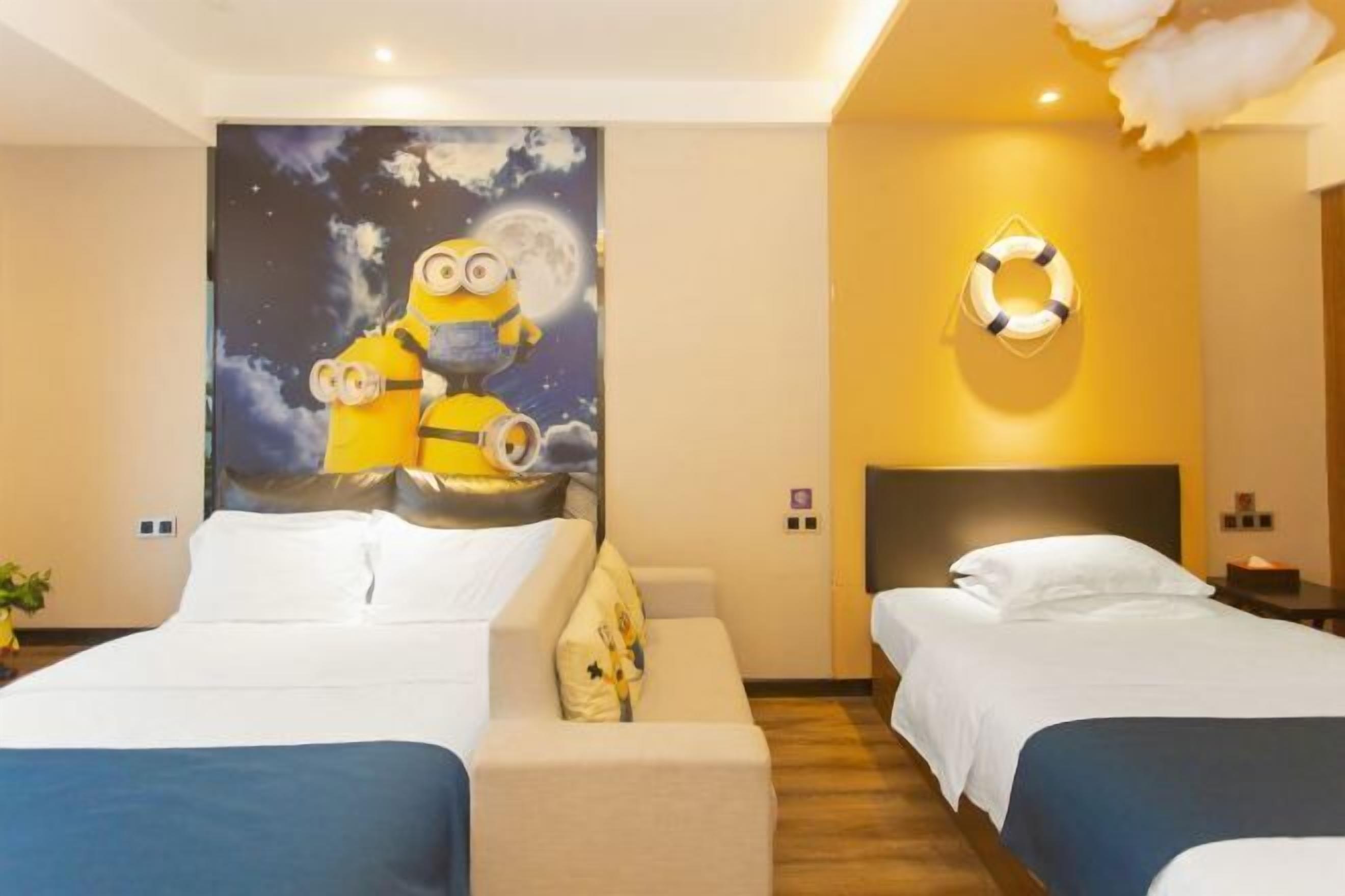 Habitación de hotel con dos camas, un mural del cielo nocturno, un adorno con forma de boia y un cabecero moderno.
