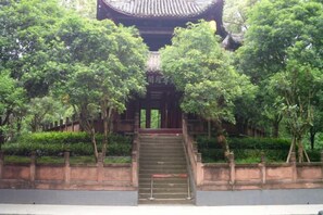 A traditional building with a staircase leading to a covered entrance, surrounded by trees. - Platinum Celebrity Hotel (Chongzhou)