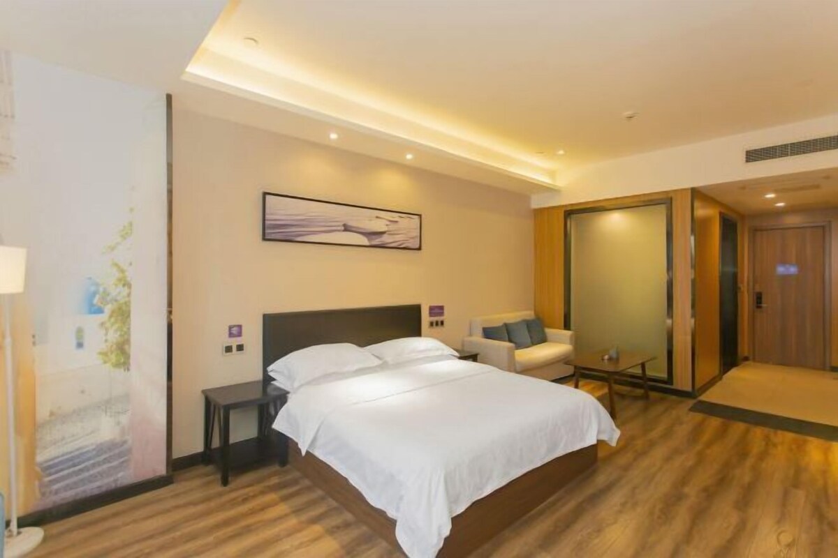 Una habitación de hotel con cama, mesita de noche, silla, una pequeña mesa, un mapa en la pared y una puerta corrediza.