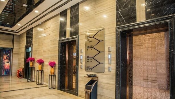 A modern hotel lobby with marble flooring, a reception desk, and a decorative wall with a geometric pattern. - Platinum Celebrity Hotel (Chongzhou)