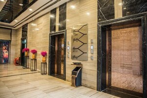 Un moderno vestíbulo de hotel con suelo de mármol, una recepción y una pared decorativa con un diseño geométrico.