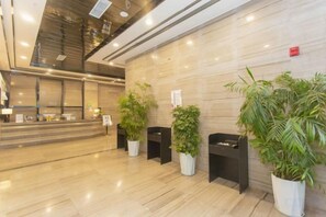 A reception area with a marble floor, a reception desk, and several potted plants. - Platinum Celebrity Hotel (Chongzhou)