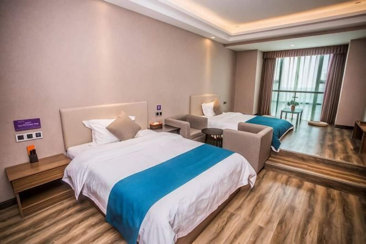 A hotel room with a large bed, a sofa, a small table, and a mirror.