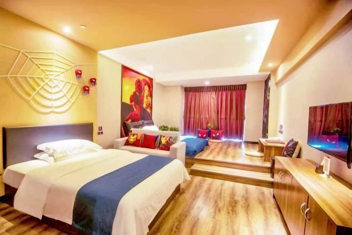 A hotel room with a bed, a seating area, a TV, and a large window.