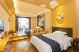 Una habitación de hotel con cama, escritorio, silla, sofá y un ventanal grande.