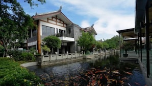 A traditional building with a koi pond in front. - Tiandi Renhe Luochenghui Hotel (Guanghan)