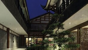 A traditional building with a courtyard, wooden beams, and a shop in the background. - Tiandi Renhe Luochenghui Hotel (Guanghan)