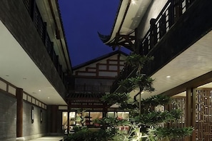 A traditional building with a courtyard, wooden beams, and a shop in the background. - Tiandi Renhe Luochenghui Hotel (Guanghan)