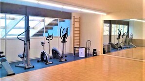 Une salle de sport équipée de matériel d’exercice, d’un miroir et d’un escalier.
