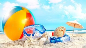 Une scène de plage avec un ballon de plage coloré, une étoile de mer, des coquillages et un parasol de plage sur le sable.