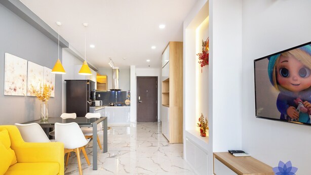 Un salon moderne avec un canapé jaune, un coin repas et une cuisine en arrière-plan.