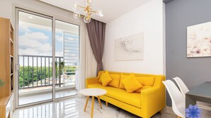 Un canapé jaune vif, une table blanche et un mur gris orné d’un tableau.