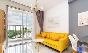 Un canapé jaune vif, une table blanche et un mur gris orné d’un tableau.
