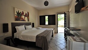 A hotel room with a bed, a desk, a chair, a television, and a painting on the wall.