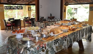 Una mesa de buffet con diferentes platillos y un mantel con motivos tropicales.