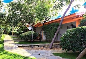Un sendero conduce a un edificio de techo rojo, rodeado de follaje y árboles.