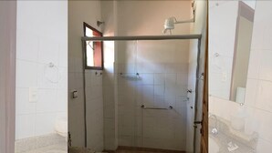 A bathroom with a glass-enclosed shower, a toilet, and a sink.