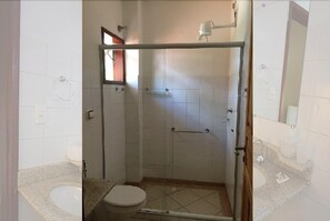 A bathroom with a glass-enclosed shower, a toilet, and a sink.