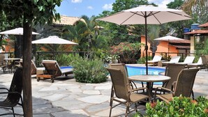 An outdoor patio area with a pool, lounge chairs, and umbrellas.