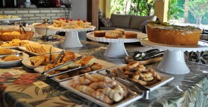 Een buffettafel met diverse soorten eten, waaronder gebak, brood en een taart op een presentatiestandaard.