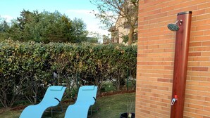 A patio area with two blue lounge chairs, a wooden door, and a small garden with white pebbles and a potted plant. - Garden level T2+Cabin direct access to the sea (Cabourg)