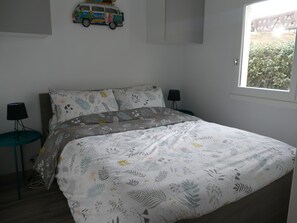 Cozy retreat with a neatly made bed, bedside tables, and a window offering a view.