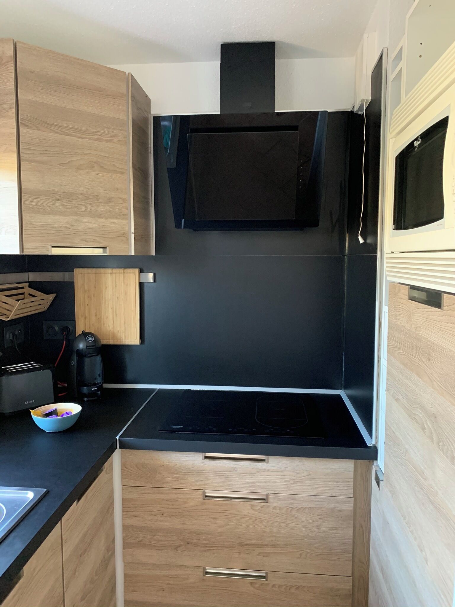 A compact kitchen with wooden cabinets, a black countertop, and a built-in stove.