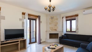 A modern living room with a flat-screen TV, a sofa, a coffee table, and a fireplace.