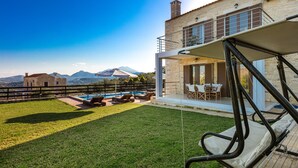 A modern house with a pool, outdoor furniture, and a view of mountains.