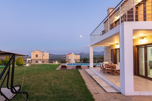 A modern house with a pool, outdoor seating, and a view of the mountains.
