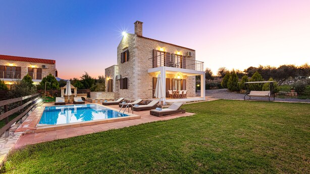 A stone house with a swimming pool, outdoor seating, and a garden.