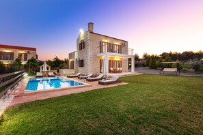 A stone house with a swimming pool, outdoor seating, and a garden.