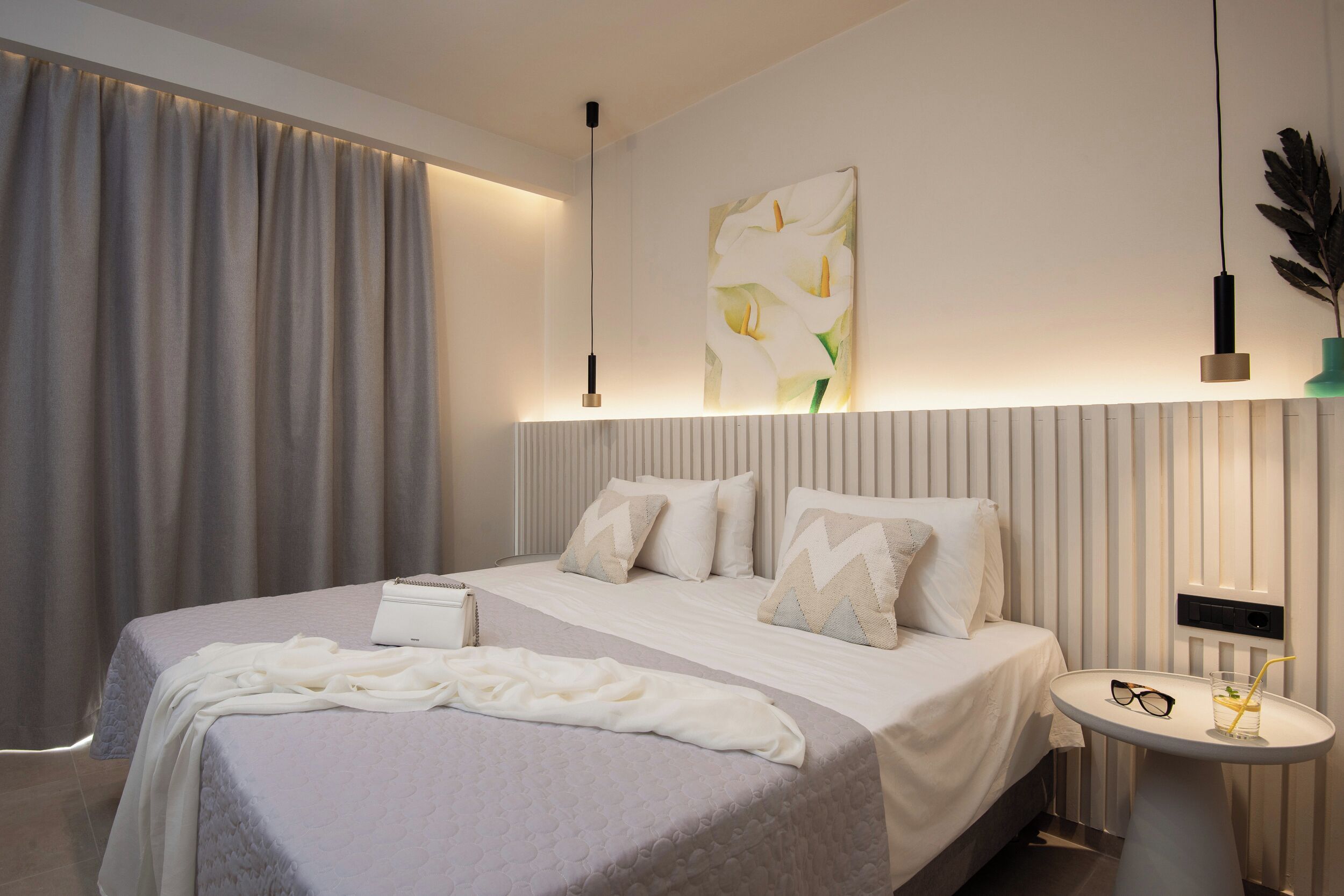 Une chambre moderne avec un grand lit, une table de chevet et un luminaire fixé au mur.