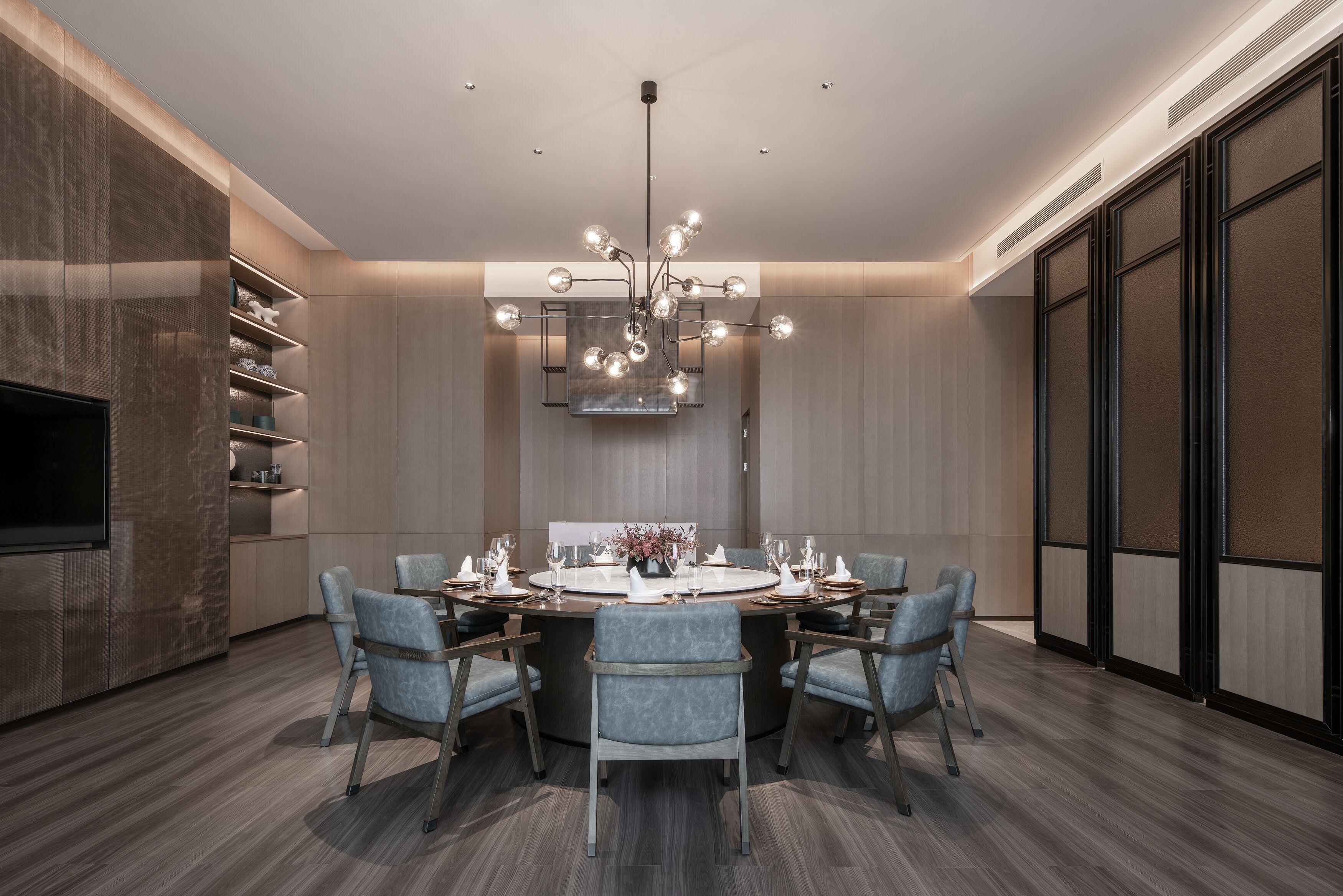 A modern dining area with a round table, six chairs, and a chandelier.