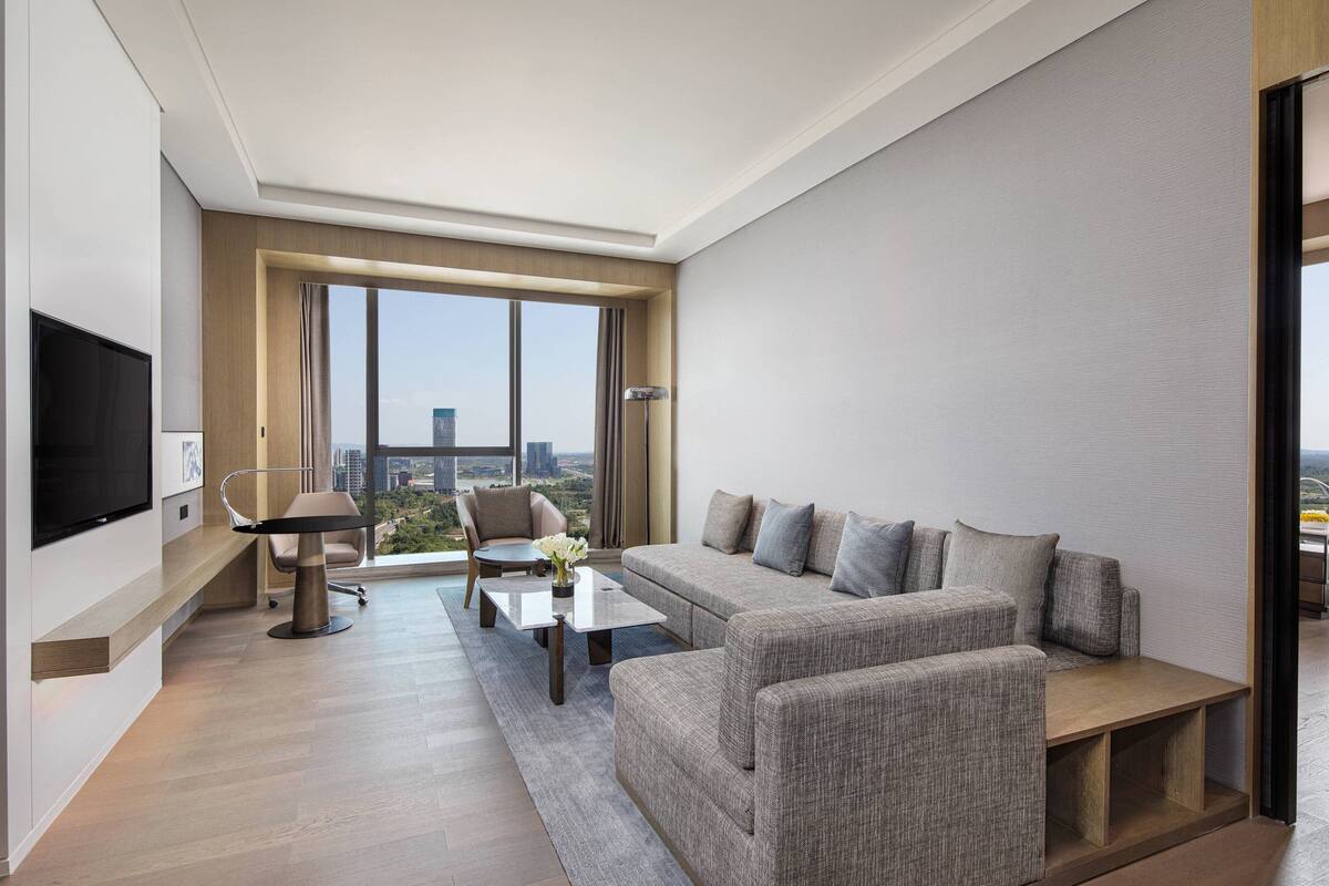 A modern living room with a sofa, armchairs, a coffee table, and a TV.