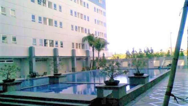 A building with a pool area, including steps leading to the pool and potted plants. - Apartement Puncak Permai Tower A by Nur Faizah (Surabaya)