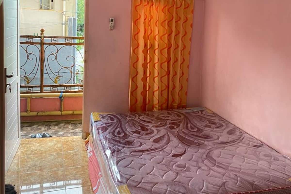 Un dormitorio pequeño con una cama individual, aire acondicionado y vistas a un balcón.