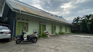 A building with a flat roof and a green door. There is a scooter parked in front. - Wisma Adhyaksa 2 (Makassar)