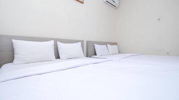 A hotel room with a large bed, white bedding, and a wall-mounted air conditioner.