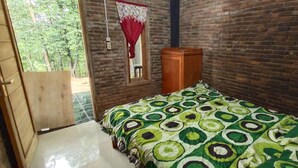 A room with a brick wall, a bed with a green and white patterned bedspread, a wooden wardrobe, and a window with a red curtain. - Homestay Kurnia - Hostel (Muntuk)