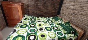 A room with a bed, a wooden cabinet, and brick walls. - Homestay Kurnia - Hostel (Muntuk)