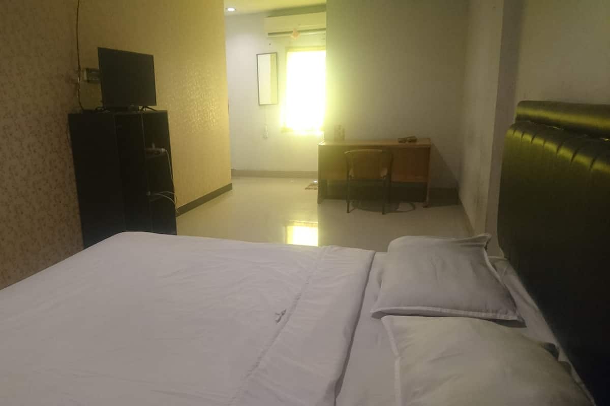 A hotel room with a bed, a desk, and a television.