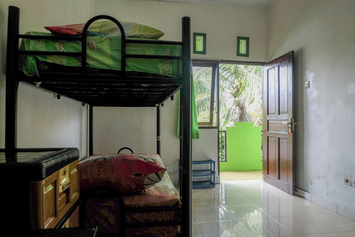 A room with bunk beds, a wooden cabinet, a green door, and a tiled floor.