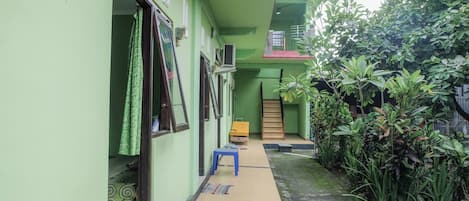 Un estrecho pasillo con un banco azul, una escalera y una pared verde.